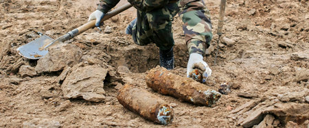 Soldier in protective gear carefully removes live mortar shell from ground during demining...