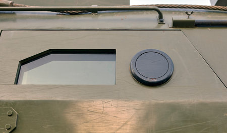 An armored vehicle features a distinct octagonal window and a circular access port, emphasizing its...
