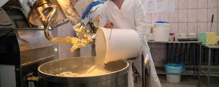 In a busy biscuit factory, a dedicated worker expertly transfers dough into a mixer, contributing to...