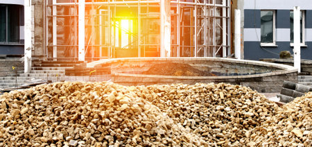 A pile of debris sits in front of a building under construction, bathed in the golden light of the...