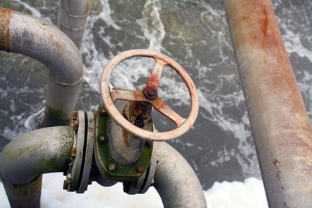 Rusty valve and pipes in an old water treatment facility illustrate past industrial methods for water purification.の写真素材