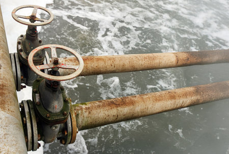 Rusty valves control water flow in an old treatment plant, showcasing the essential process of water purification along the riverbank.の写真素材