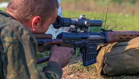 A soldier is focusing through the scope of a sniper rifle, participating in shooting practice on...