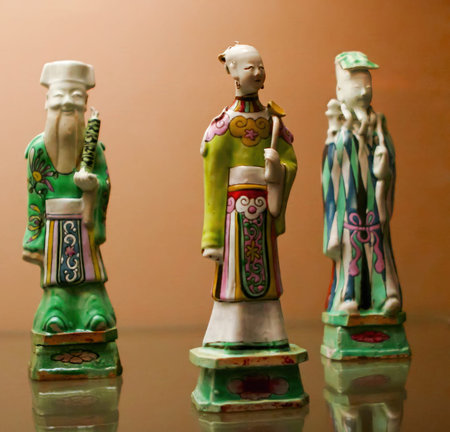Porcelain figurines representing traditional Chinese figures stand elegantly on a reflective...