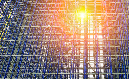 Scaffolding structures dominate the skyline as the sun sets, casting a warm glow on the busy...