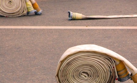 Fire hoses rolled and ready at a training ground during a sunny afternoon in a city parkの写真素材