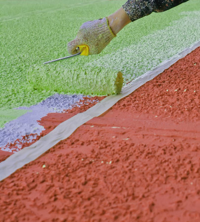 A person applies vibrant paint to an outdoor surface, creating a bold, abstract design with shades...