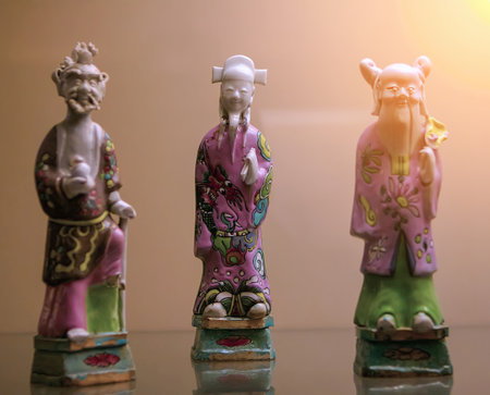 Three intricately designed ceramic figurines in vibrant colors are showcased against a soft light backdrop, capturing cultural artistry.の写真素材