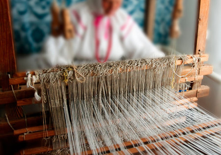 A skilled artisan works diligently at a wooden loom, weaving fine threads into intricate patterns...