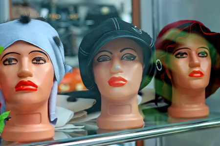 Mannequin heads showcase a variety of trendy hats, including elegant styles, in a boutique during daylight hours.の写真素材