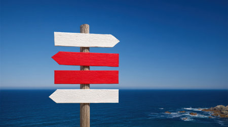 A vibrant signpost stands by the shore, displaying arrows in bold colors, guiding visitors to various destinations by the seaside.の素材