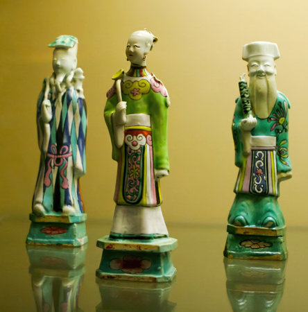 Three meticulously crafted Chinese figurines stand on a reflective surface, displaying intricate details and colorful clothing that highlight traditional artistry.の写真素材