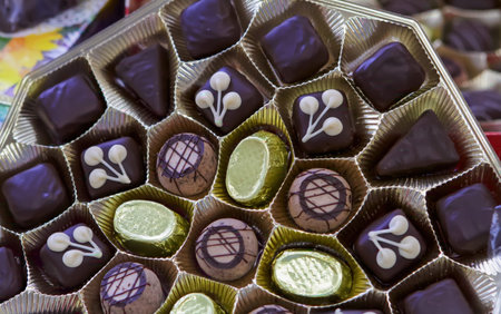 Colorful assorted chocolate candies are neatly arranged in a decorative box, showcasing their...