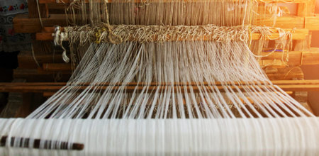 Skilled artisans weave intricate patterns using a loom in a workshop filled with natural light...