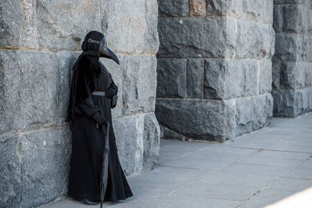 plague doctor stands against a stone wallの写真素材