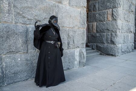 plague doctor stands against a stone wallの写真素材