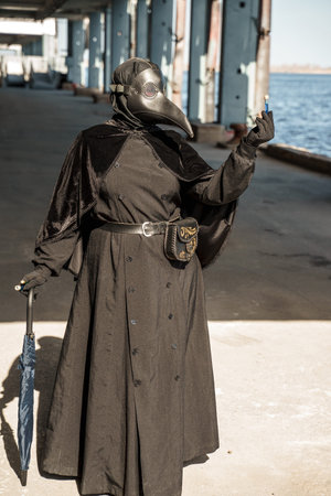 plague doctor in empty city on empty pier holds vaccineの写真素材
