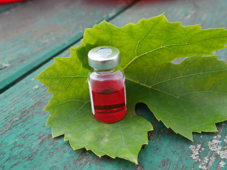 ampoule with red medicament on the background of an old green tableの写真素材
