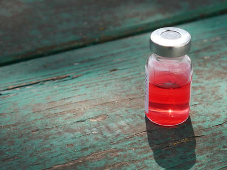 ampoule with red medicine on the old tableの写真素材