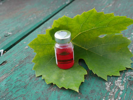 ampoule with red medicament on the background of an old green tableの写真素材