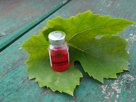 bottle with red medicine on the background of a leafの写真素材