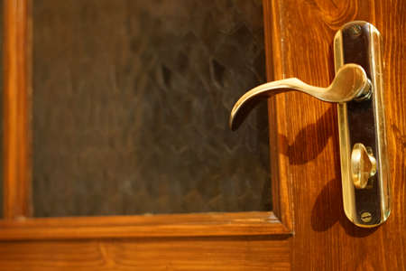 A closed wooden door and a gold handle. Home refined interior.の写真素材