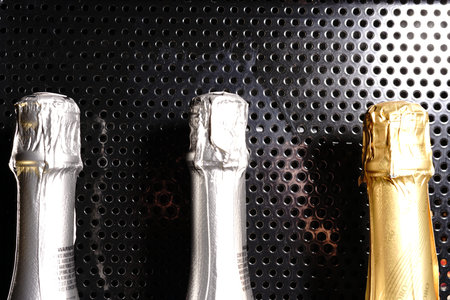 Three bottles of champagne lie on a black metal table. The top of the bottles.