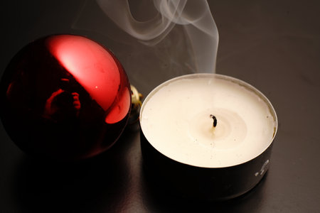 Candle and Christmas toy on black background. Dim lights.の写真素材