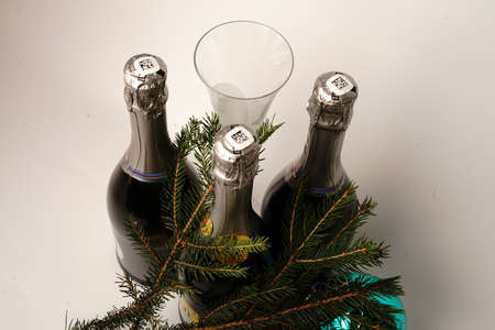 Champagne bottles on a white background. Around the branches of the Christmas tree and Christmas toys. Champagne glass.の写真素材