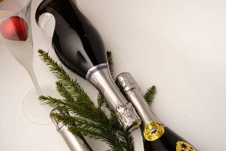 Champagne bottles on a white background. Around the branches of the Christmas tree and Christmas toys. Champagne glass.の写真素材
