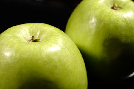 A green apples on a black background. Closeup. The light was dim.の写真素材