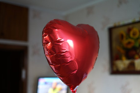 A heart inflated with helium flies on a string at home. A gift for Valentines Day.の写真素材