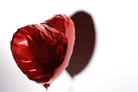 A heart inflated with helium flies on a string on a white background. A gift for Valentines Day.の写真素材