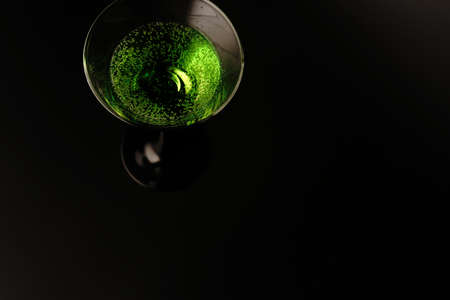 Two glasses with a green cocktail on a black background. One glass is full and the other is emptyの写真素材