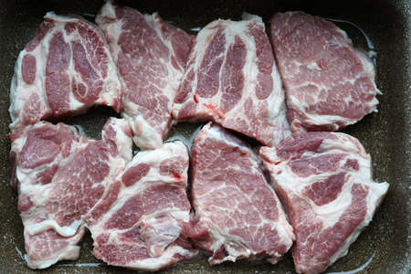 Raw pieces of pork laid in a bowl for further baking in the oven. In the kitchen.の写真素材