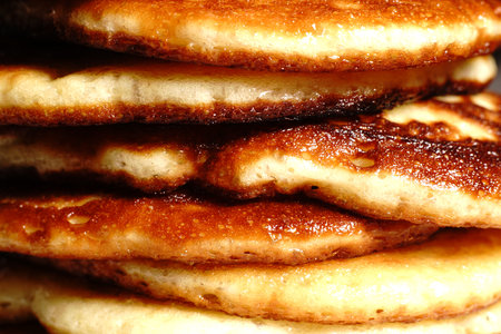 Golden pancakes lie on a plate, one on top of the other. Closeup.