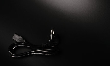 The electric power wire for the PC is black on a black background and a place for text. Dimmed...