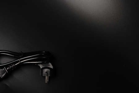 The electric power wire for the PC is black on a black background and a place for text. Dimmed lights.の写真素材