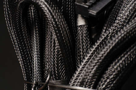 Black braided wires in a large bundle on a black background. Close. Dimmed lightsの写真素材