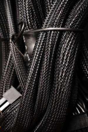 Black braided wires in a large bundle on a black background. Close. Verticallyの写真素材