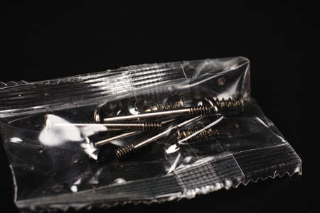 Bolts in a vacuum bag for mounting devices on a black insulated background.の写真素材
