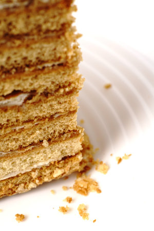 A piece of homemade honey cake with many layers on a white plate. Close