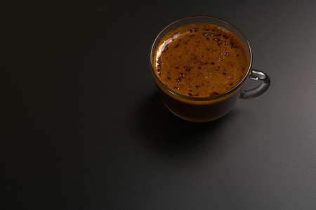A cup of black coffee stands on a black background.Dimmed lights and a view from above. Space for textの写真素材