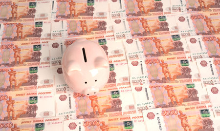 A piggy bank in the form of a pink pig stands on the texture of five-thousand-ruble bills.の写真素材