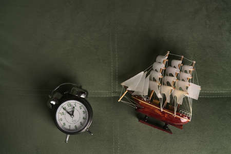 Moscow, Russia - june 8 2021: A model of a small boat and an old-style alarm clock. The concept of travel and passing time. Flatlayのeditorial素材
