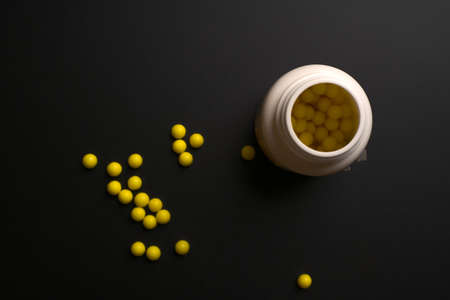 Tablets with a bottle of them on a black background.の写真素材