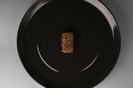 A piece of chocolate with nuts is placed on a black plate.の写真素材