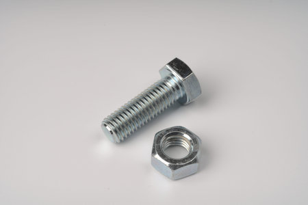 A large metal threaded bolt and a nut for it side by side on a white background.