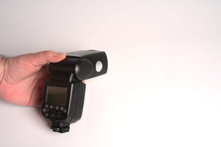 Moscow, Russia - june 7 2021: Flash for photos in your hand on a white background. Space for the...