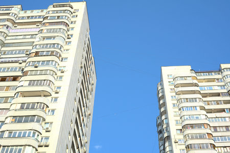 Two high-rise buildings are next to each other and there is a blue sky between them. View from below...